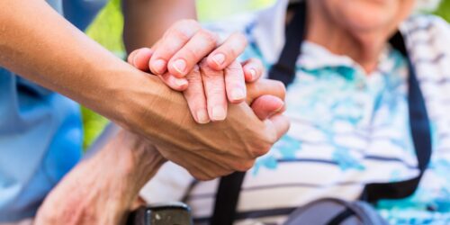 Nurse consoling senior woman holding her hand